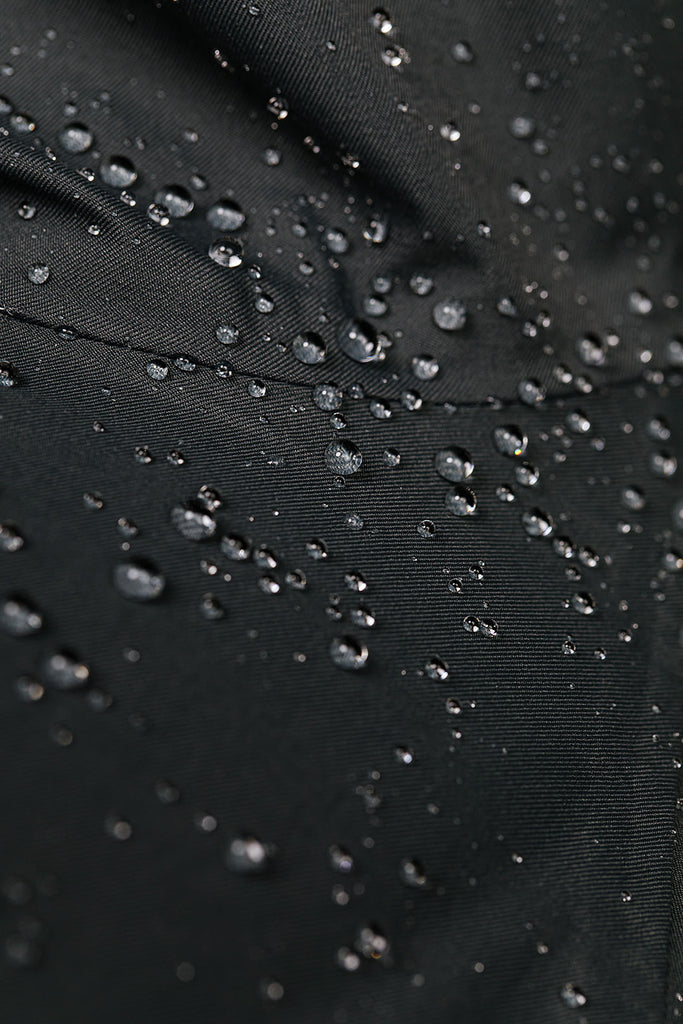 Close up of water beads on waterproof fabric and seam of San Poncho rain jacket in Midnight black